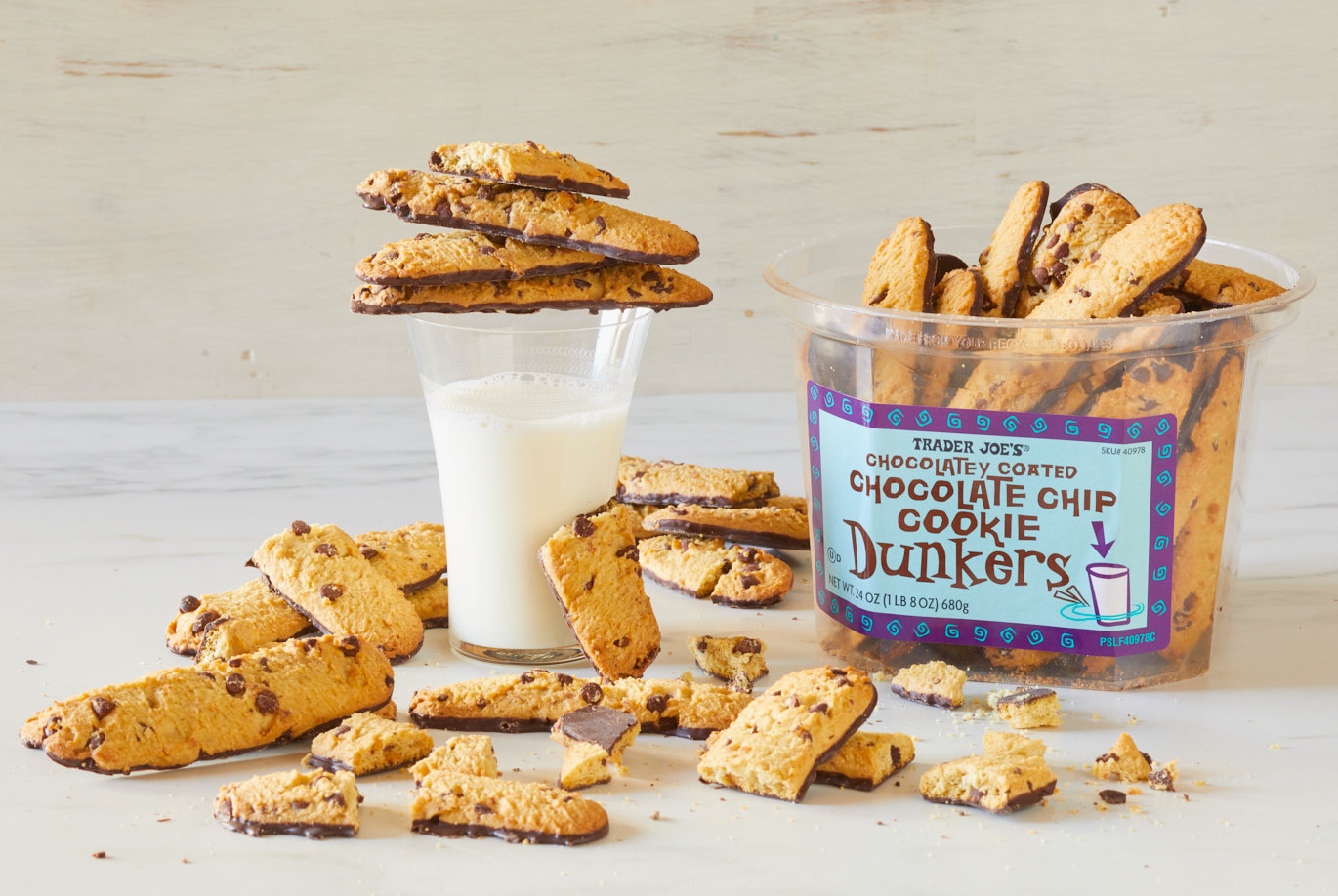 Trader Joe's Chocolatey Coated Chocolate Chip Cookie Dunkers; many cookies on surface, and stacked atop a tall glass of milk