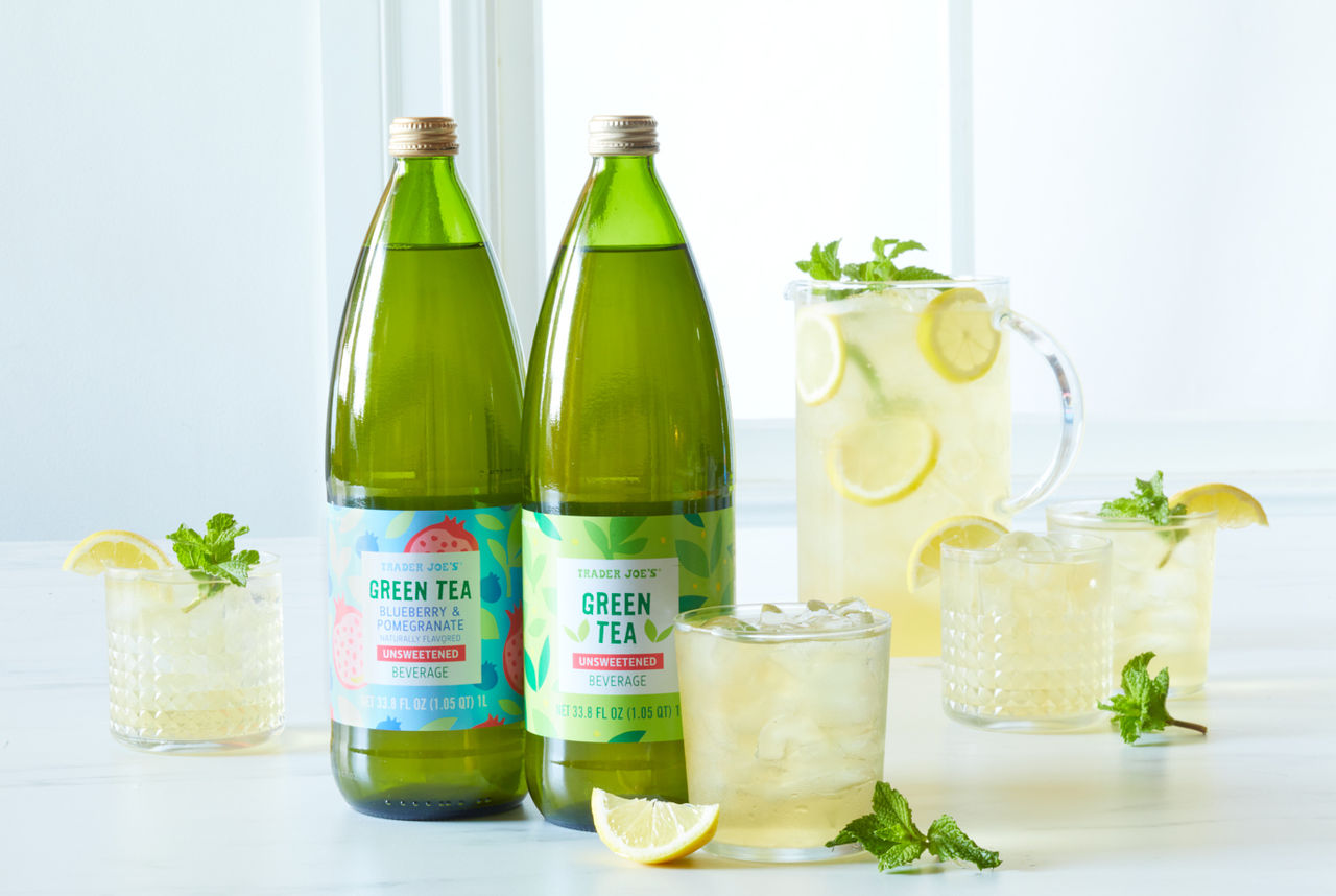 Trader Joe's Unsweetened Green Tea, and Unsweetened Blueberry Pomegranate Green Teas; against bright white surface & background, in pitcher and glasses filled with ice, lemon wedge and mint