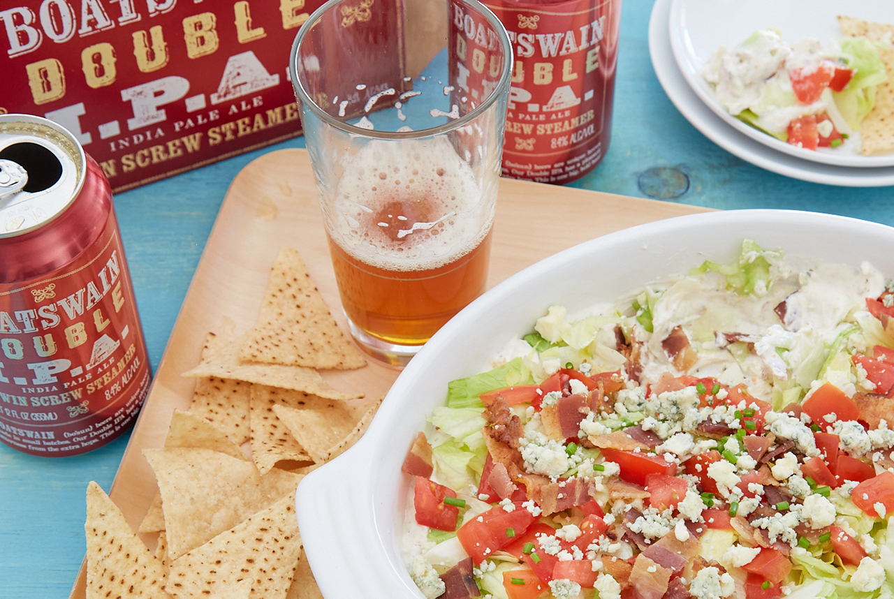 Boatswain Double IPA in a glass next to creamy wedge salad dip recipe with white corn tortilla chips