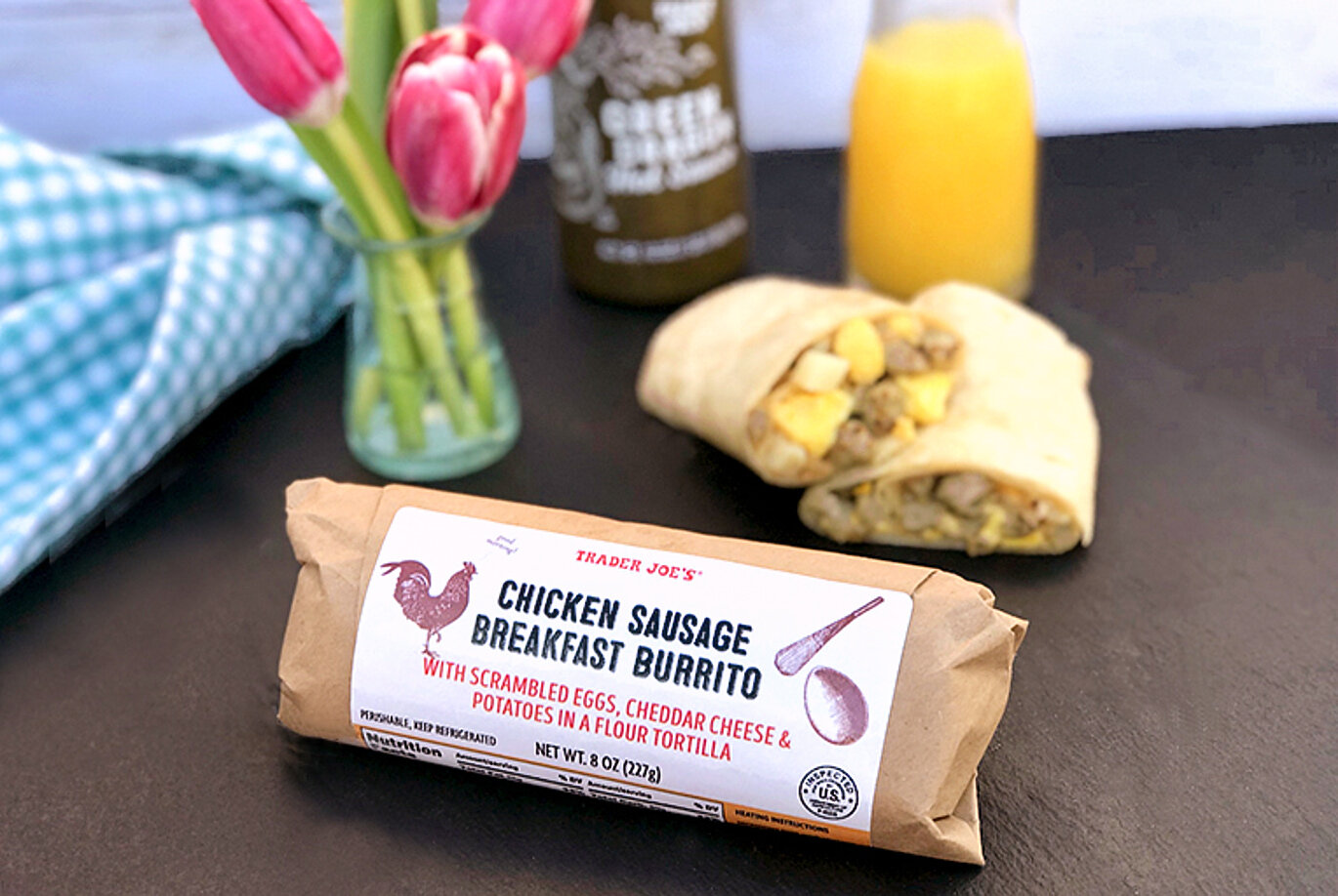 Trader Joe's Chicken Sausage Breakfast Burrito; shown cut in half in background, with orange juice and Green Dragon Sauce