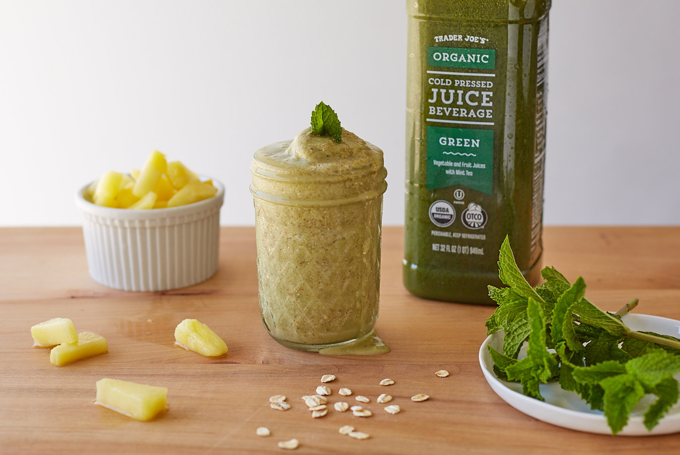 Trader Joe's Organic Cold Pressed Green Juice Beverage; shown blended and served in small mason jar as a smoothie with oats, pineapple tidbits and mint garnish