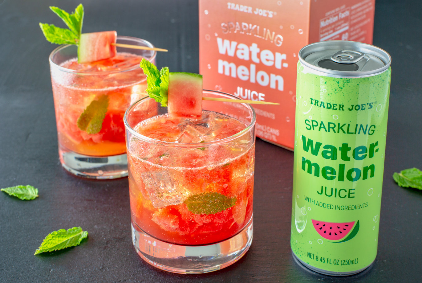 Trader Joe's Sparkling Watermelon Juice; showin in short glass over ice, garnished with watermelon cubes and mint leaves