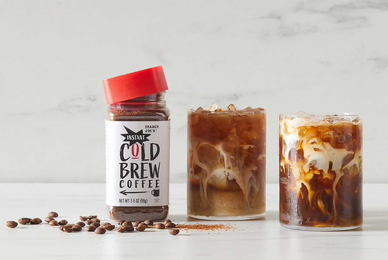 Trader Joe's Instant Cold Brew Coffee; white marble surface and background; Instant Cold Brew over ice in a glass, with a splash of milk swirling to the bottom