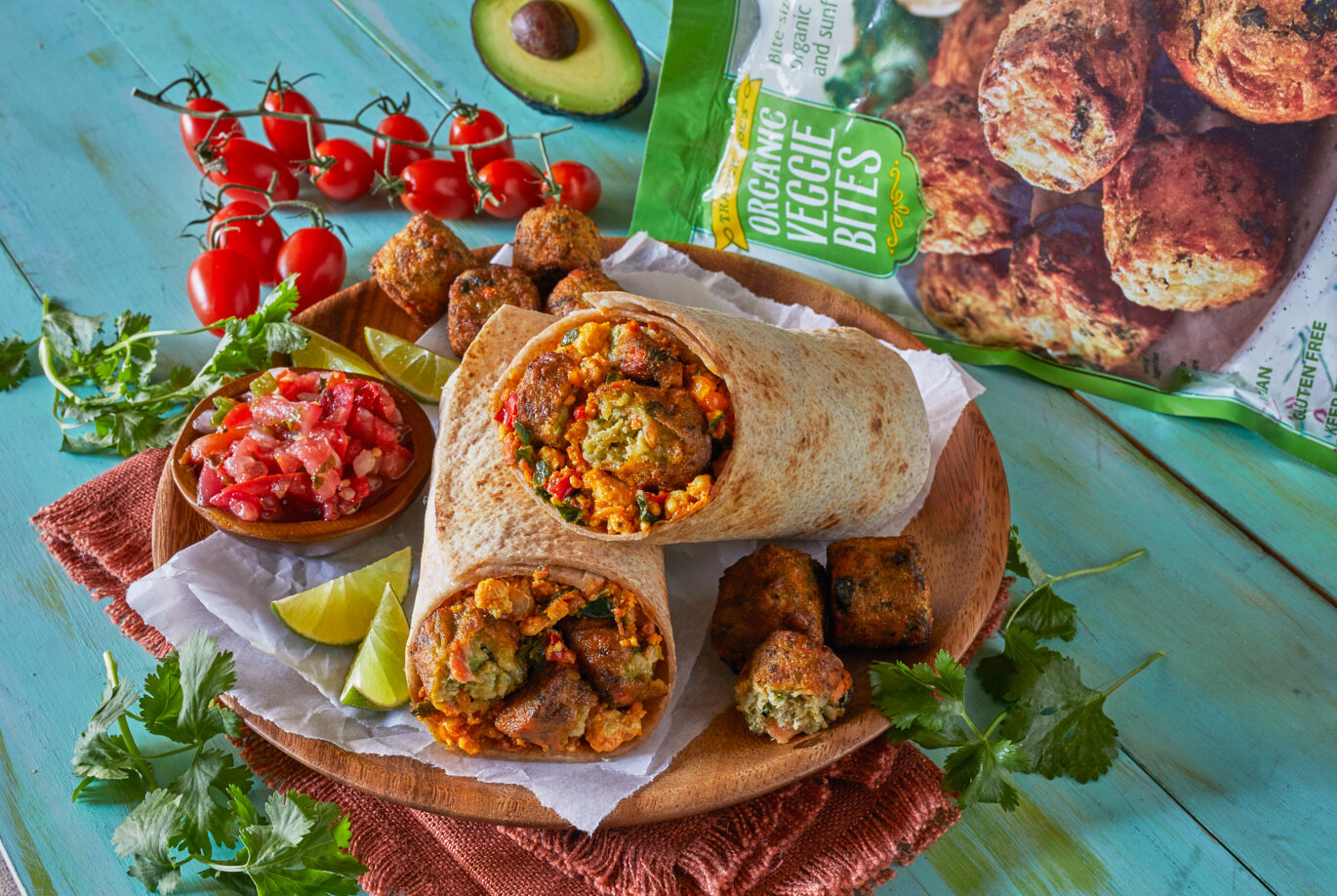 Vegan breakfast burritos shown with Trader Joe's Organic Veggie Bites and Tofu Scramble rolled up in a tortilla. Side of pico de gallo and lime wedges