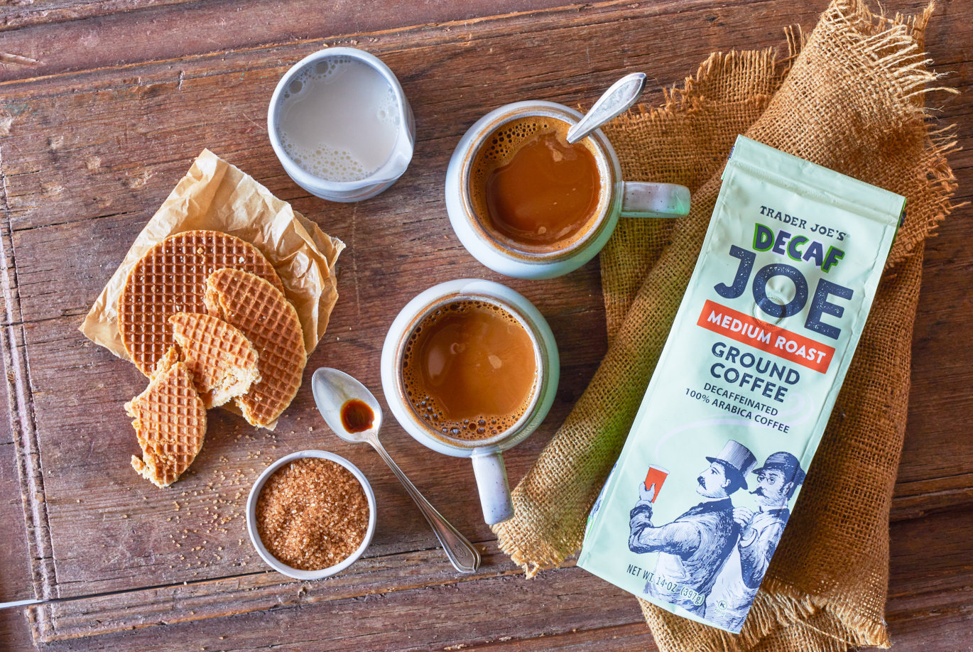 Trader Joe's Decaf Joe Medium Roast Ground Coffee; in two mugs with small containers of cream and sugar on left, and a couple Stroopwafel cookies on surface