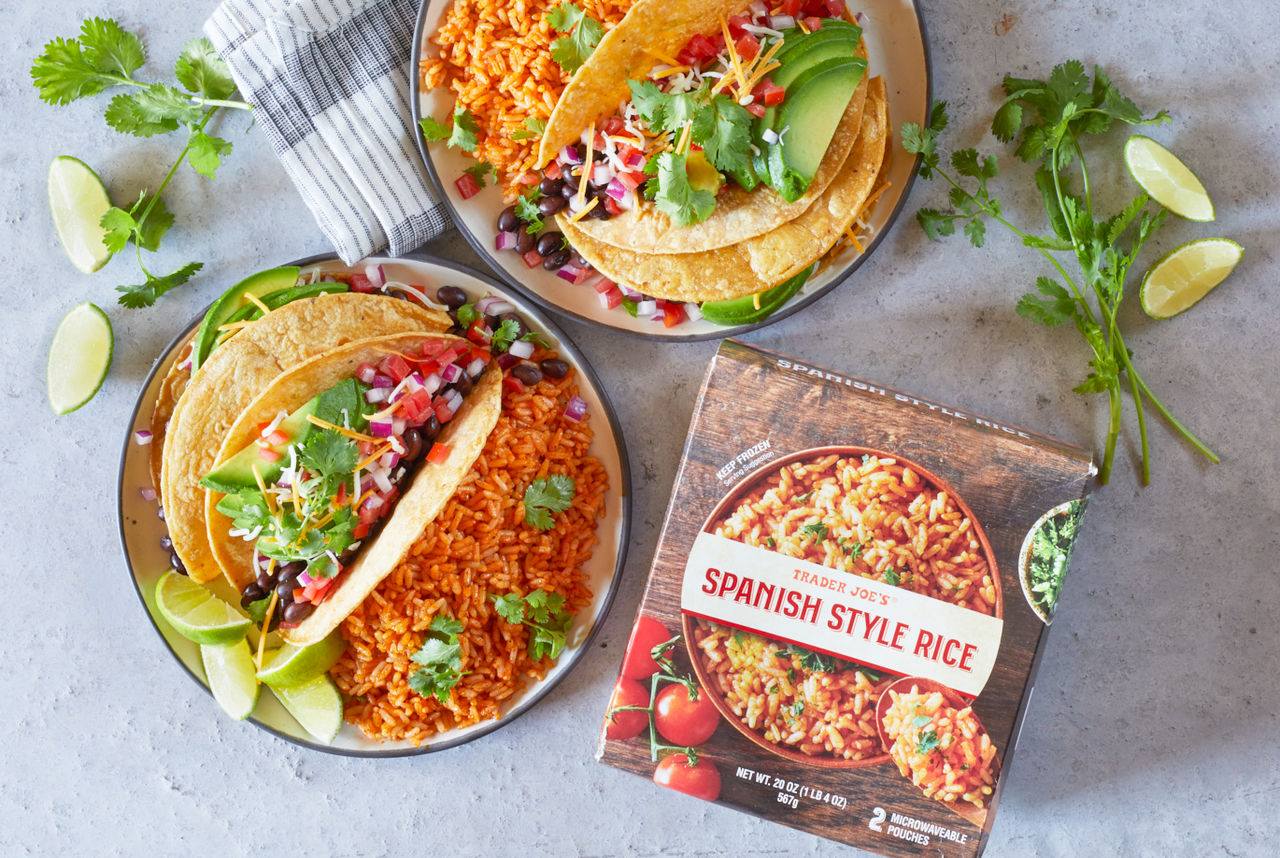 Trader Joe's Spanish Style Rice; on two plates, served alongside tacos with beans, avacado, onion, tomato, cilantro and lime wedges