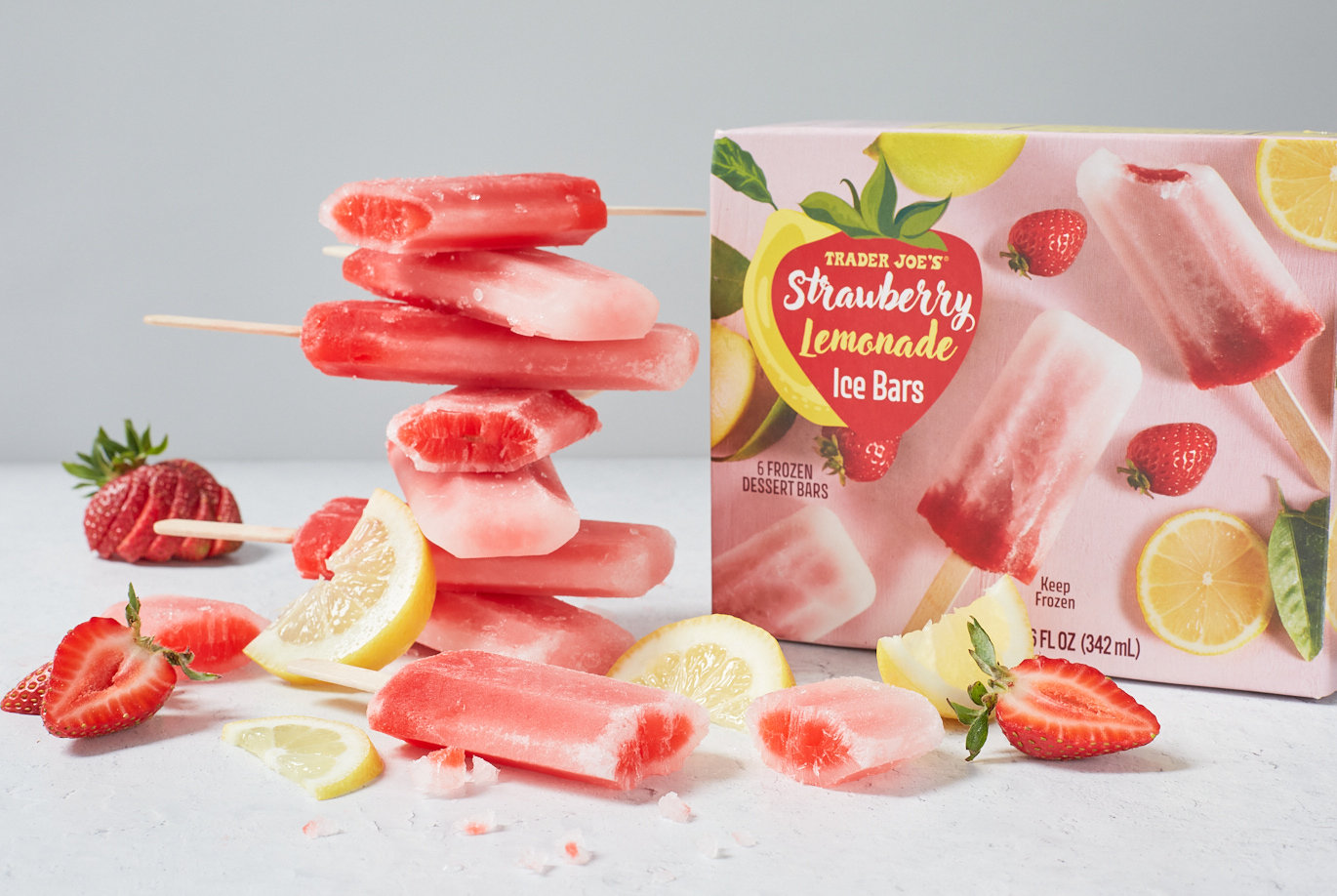 Trader Joe's Strawberry Lemonade Ice Bars; many stacked into a tower, a coupe broken to see inside; strawberries and lemon slices on surface