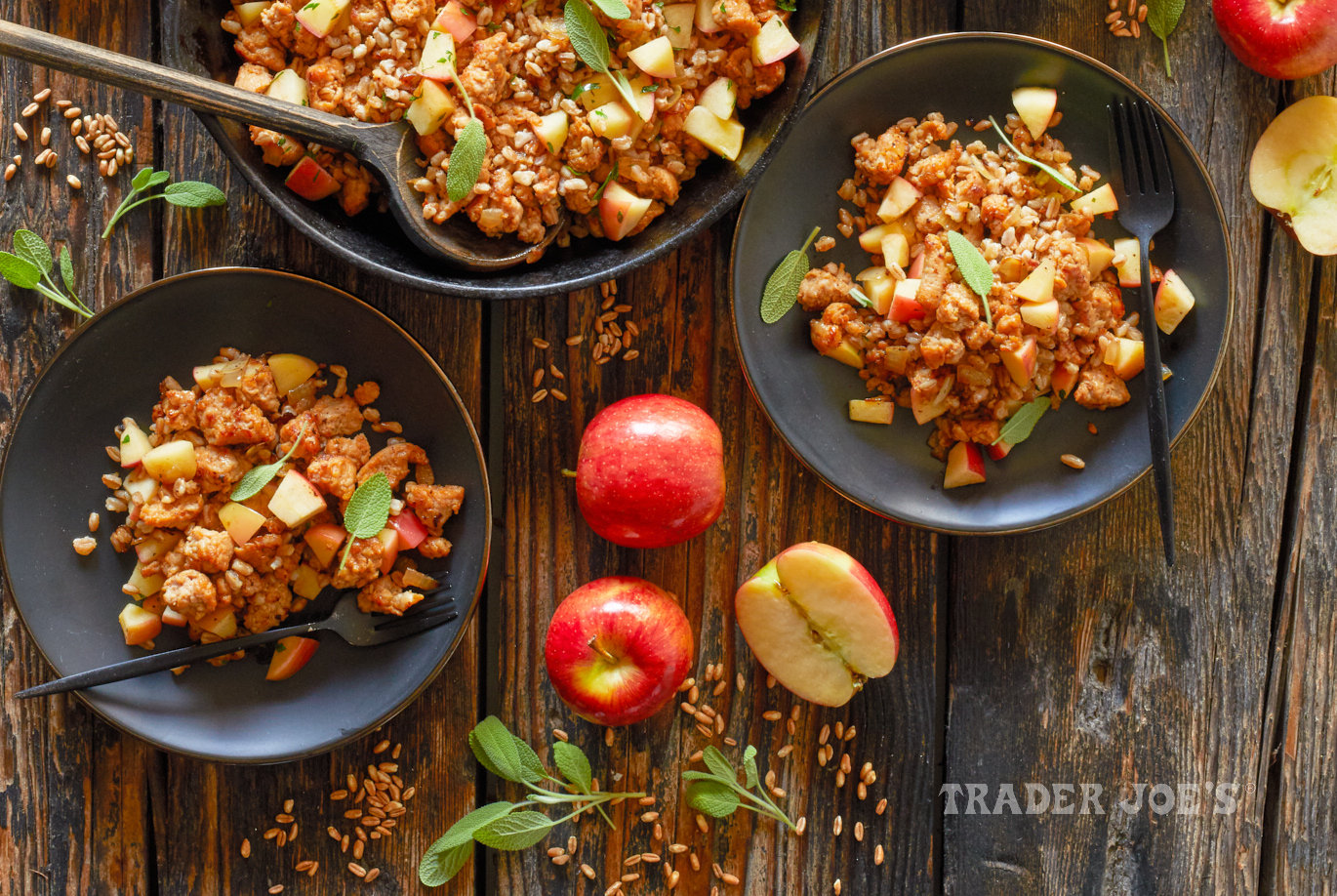 Trader Joe's Honeycrisp Apples used in recipe for Farro with Chicken Sausage; served in a cast iron skillet and two plates, dried farro, more apples and sage leaves on surface