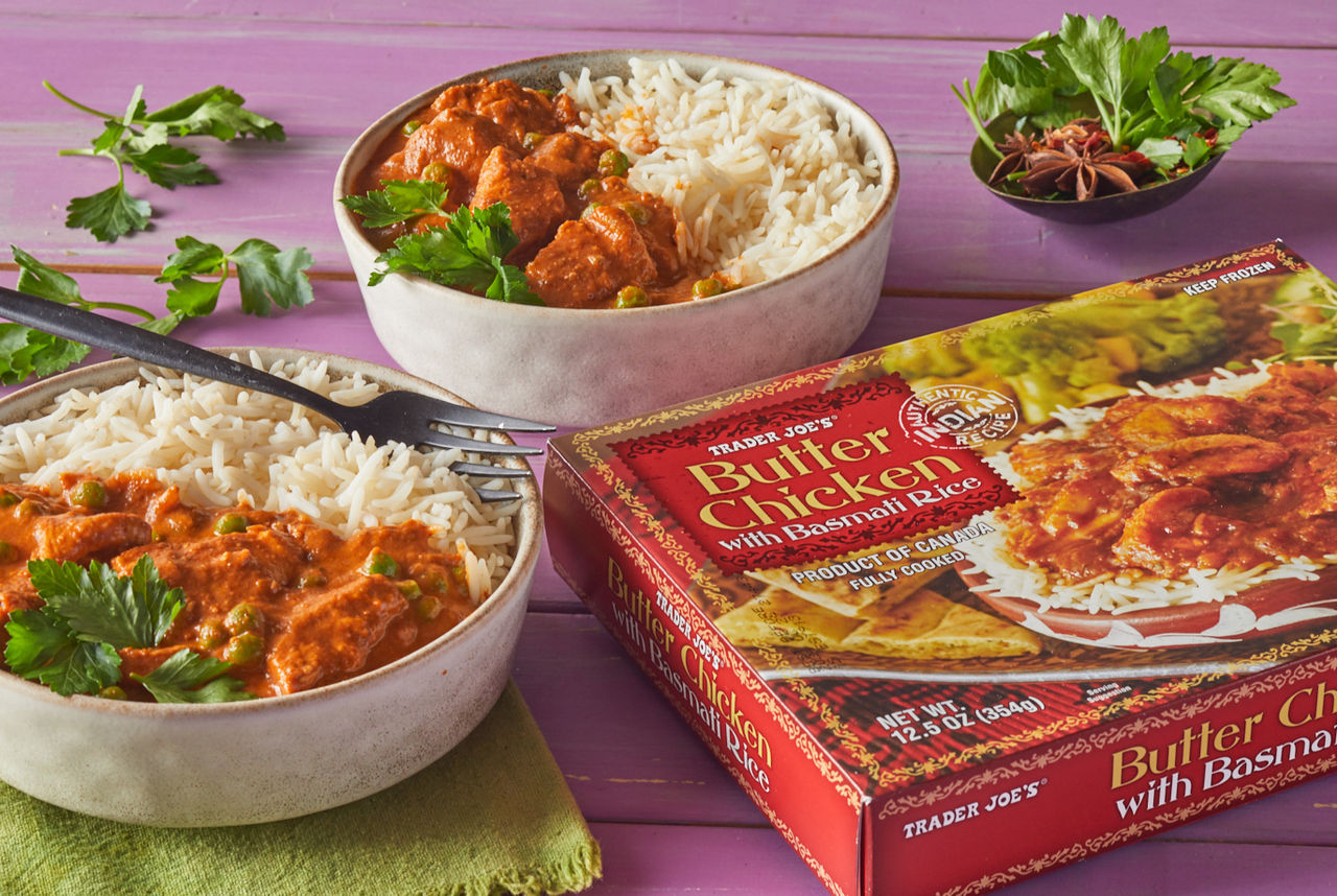 Trader Joe's Butter Chicken with Basmati Rice; presented in two bowls, topped with peas and fresh parsley; on purple background